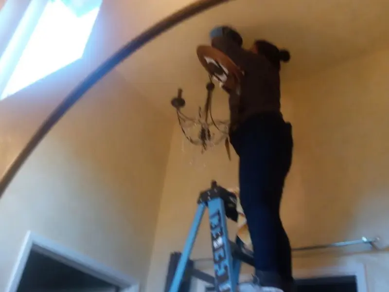 Electrician installing a chandelier in a Rice residence
